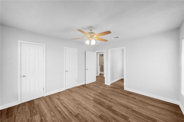 unfurnished bedroom with a textured ceiling, dark hardwood / wood-style floors, and ceiling fan