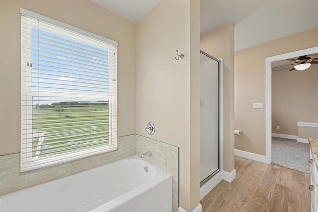 bathroom featuring ceiling fan, plus walk in shower, and hardwood / wood-style flooring