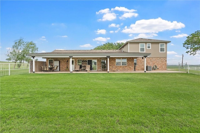 back of property with central air condition unit, a patio area, and a yard