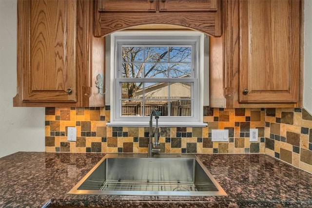 kitchen with backsplash, dark stone counters, and sink