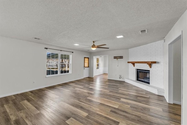 unfurnished living room featuring a fireplace, a textured ceiling, and dark hardwood / wood-style flooring