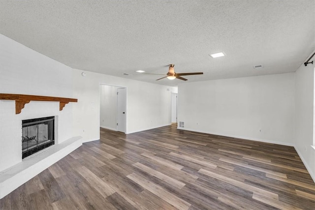 unfurnished living room with ceiling fan, dark hardwood / wood-style flooring, and a textured ceiling