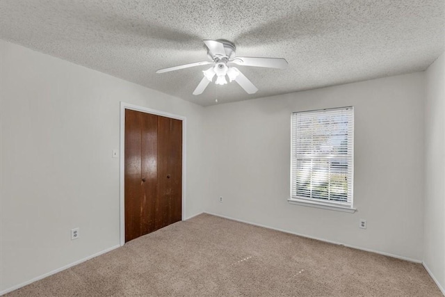 unfurnished bedroom with ceiling fan, a closet, carpet, and a textured ceiling