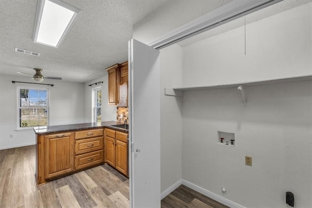 interior space featuring ceiling fan, a textured ceiling, hookup for a washing machine, and light hardwood / wood-style flooring