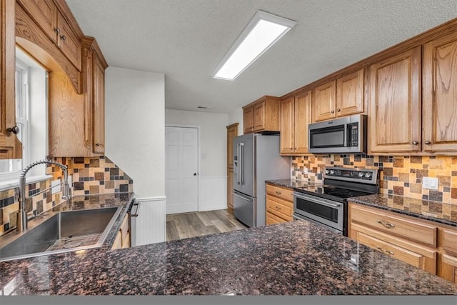 kitchen with backsplash, stainless steel appliances, light hardwood / wood-style flooring, and sink