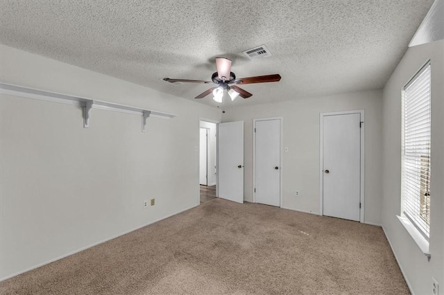 unfurnished bedroom with carpet flooring, multiple windows, ceiling fan, and a textured ceiling