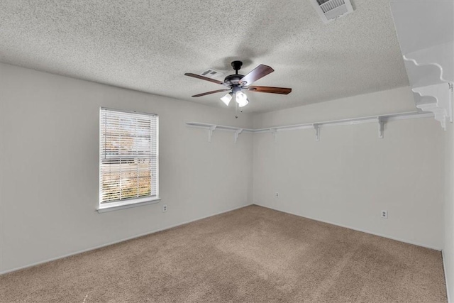 carpeted empty room with ceiling fan and a textured ceiling