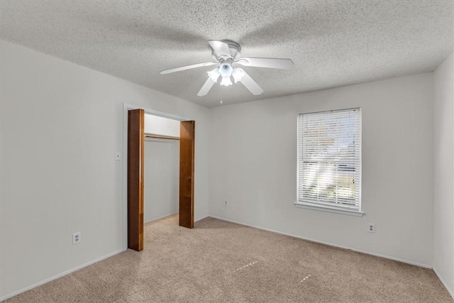 unfurnished bedroom with ceiling fan, a textured ceiling, light carpet, and a closet