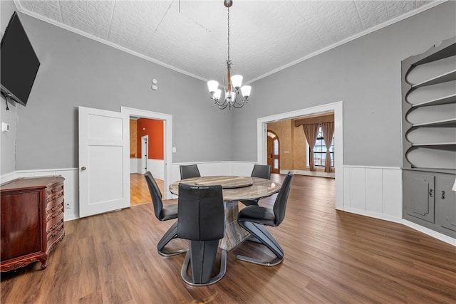 dining room with an inviting chandelier, hardwood / wood-style floors, ornamental molding, and a textured ceiling