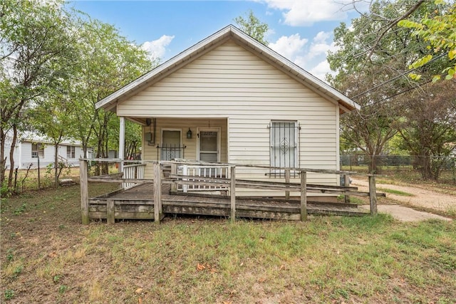 view of front of home with covered porch, a front yard, and fence