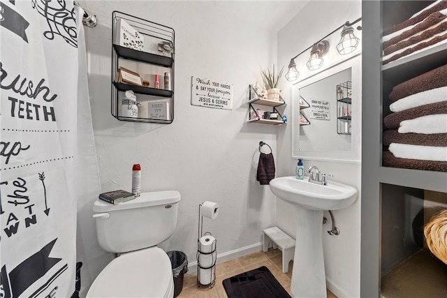 bathroom featuring toilet, a shower with shower curtain, tile patterned floors, and sink