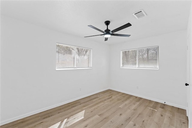 unfurnished room featuring light wood finished floors, plenty of natural light, visible vents, and baseboards