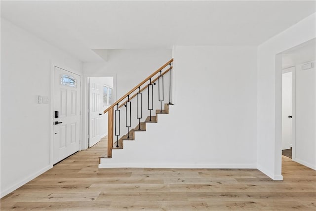 foyer entrance with stairway, baseboards, and wood finished floors