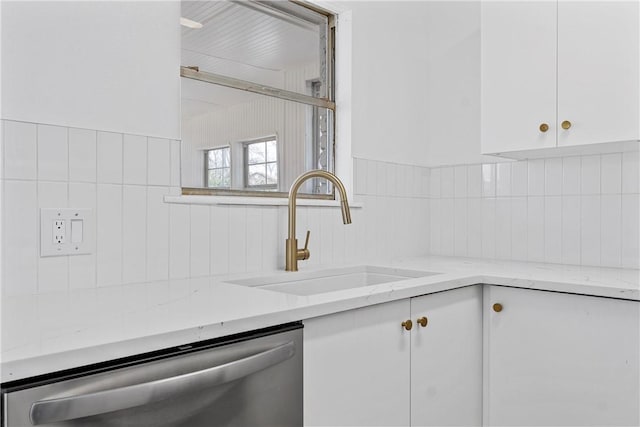 kitchen with tasteful backsplash, white cabinets, dishwasher, light stone countertops, and a sink