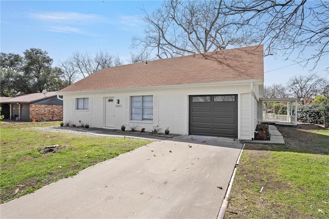 view of front of property featuring a garage, brick siding, concrete driveway, roof with shingles, and a front yard