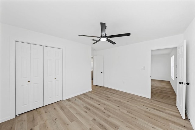 unfurnished bedroom with light wood finished floors, ceiling fan, baseboards, and a closet