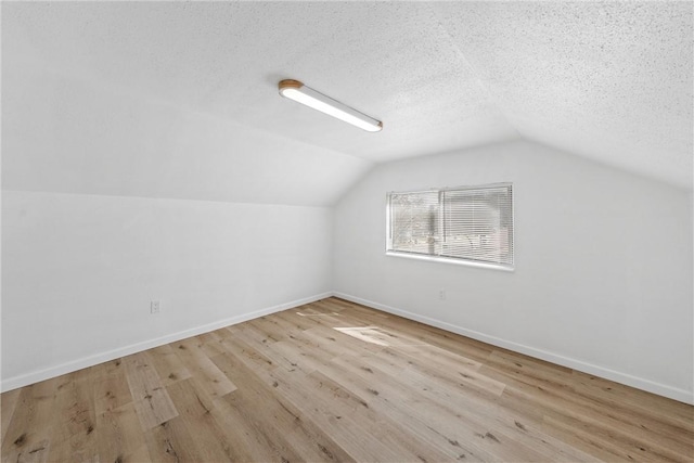 additional living space with a textured ceiling, baseboards, and wood finished floors