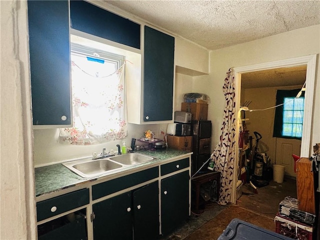 kitchen featuring a sink, a textured ceiling, a healthy amount of sunlight, and dark cabinets