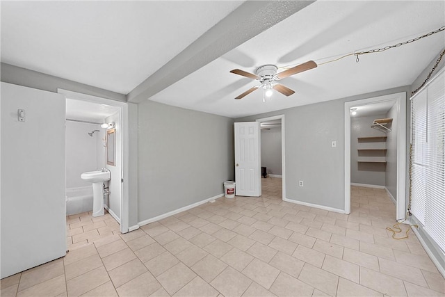 unfurnished bedroom featuring light tile patterned floors, baseboards, freestanding refrigerator, a closet, and a walk in closet