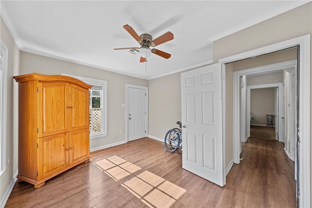 bedroom featuring crown molding, baseboards, light wood-type flooring, and ceiling fan