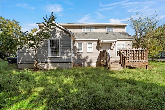 back of property featuring a wooden deck and a yard