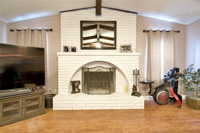 living room featuring vaulted ceiling with beams, a fireplace, hardwood / wood-style floors, and a textured ceiling