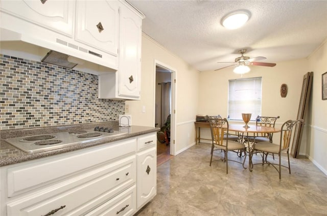 kitchen with white stovetop, tasteful backsplash, white cabinetry, ceiling fan, and a textured ceiling