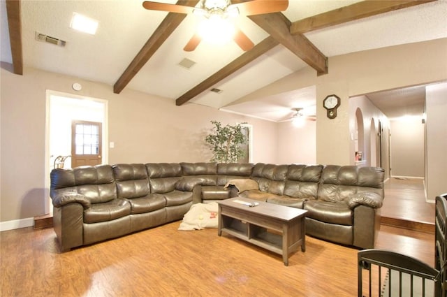 living room with ceiling fan, light hardwood / wood-style floors, and vaulted ceiling with beams