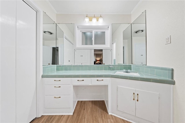 bathroom with hardwood / wood-style flooring, vanity, decorative backsplash, and ornamental molding