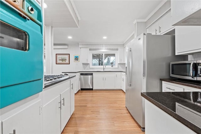 kitchen featuring decorative backsplash, white cabinetry, light hardwood / wood-style floors, and appliances with stainless steel finishes