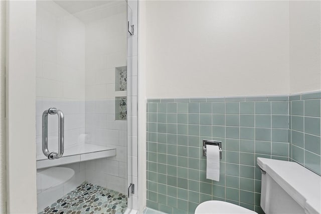 bathroom with a shower with door, toilet, and tile walls