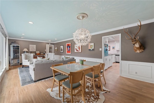 dining space featuring light hardwood / wood-style floors, ornamental molding, and an inviting chandelier