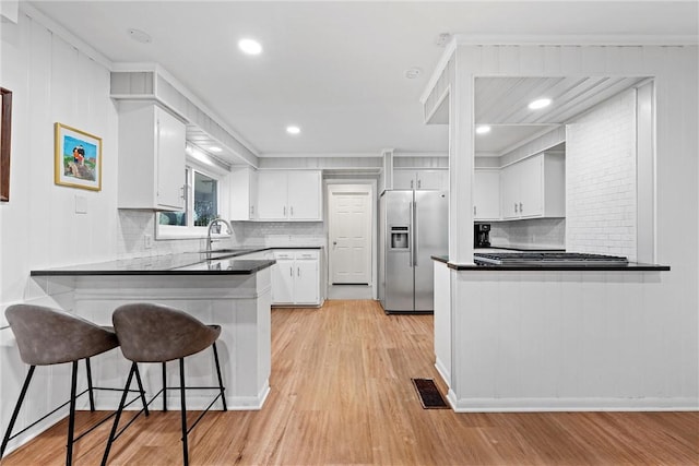 kitchen featuring white cabinets, stainless steel refrigerator with ice dispenser, kitchen peninsula, and light hardwood / wood-style floors