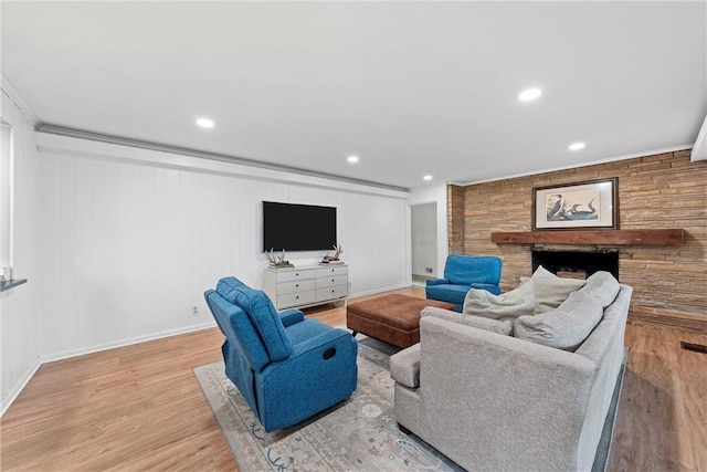 living room with a fireplace, light wood-type flooring, crown molding, and wood walls