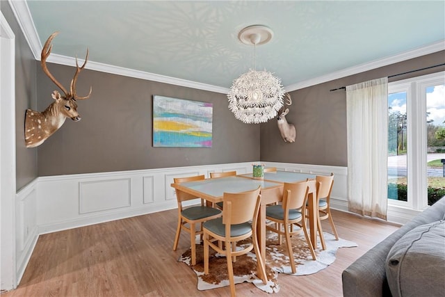 dining area with light hardwood / wood-style flooring, ornamental molding, and a notable chandelier