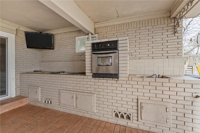 kitchen with beam ceiling, oven, and brick wall