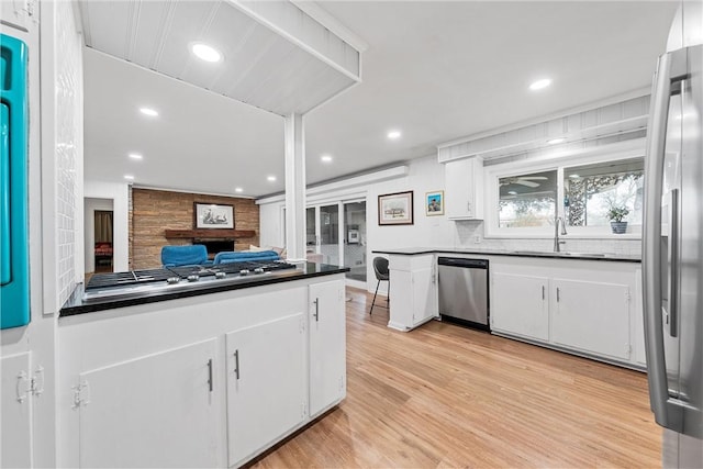 kitchen featuring sink, light hardwood / wood-style flooring, decorative backsplash, white cabinetry, and stainless steel appliances