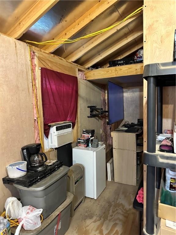 basement featuring cooling unit and white refrigerator