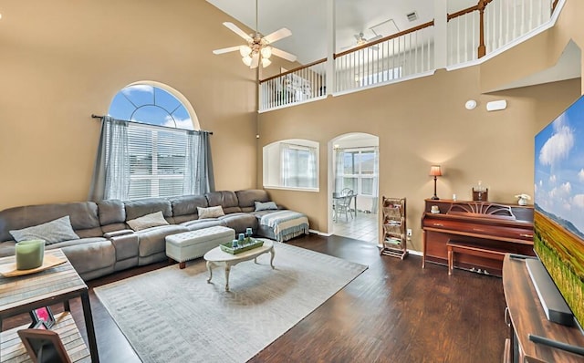 living room featuring dark hardwood / wood-style floors, ceiling fan, and a high ceiling