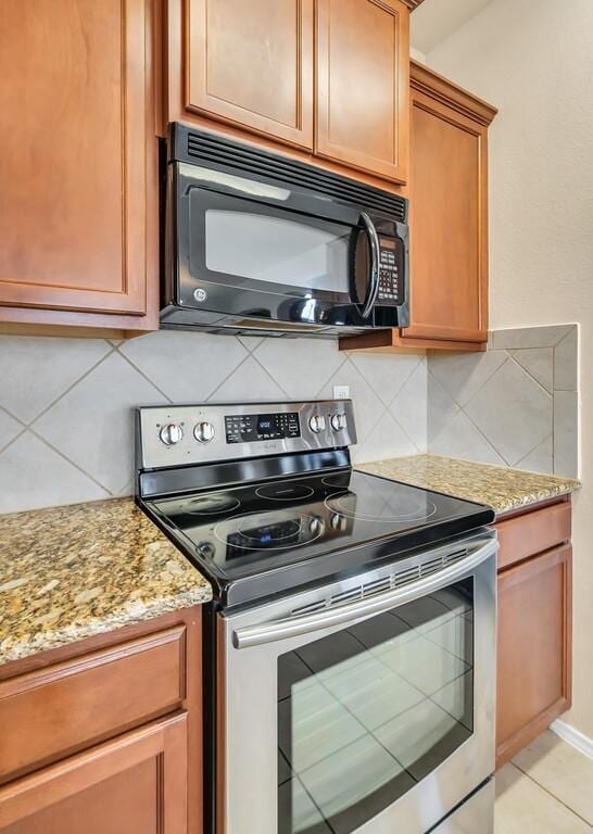 kitchen featuring electric stove, decorative backsplash, and light stone counters