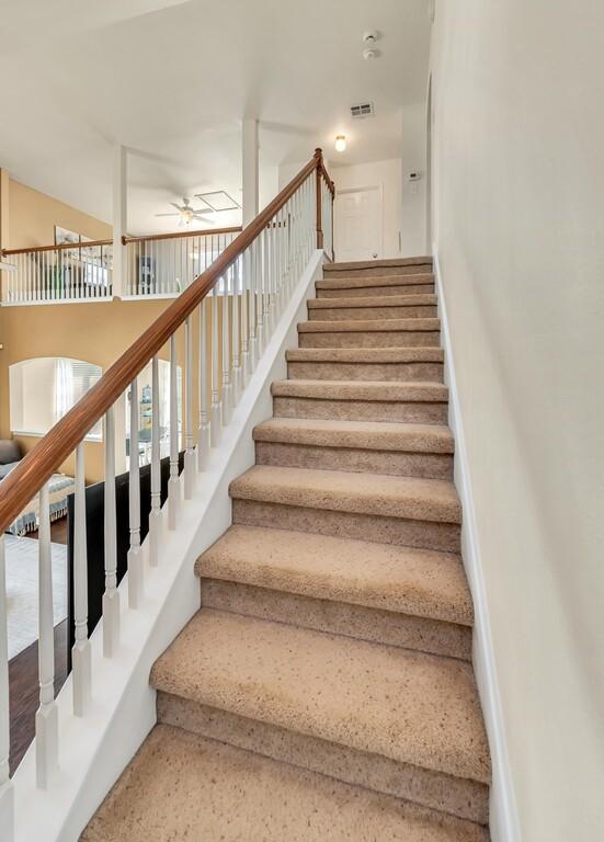 staircase featuring ceiling fan