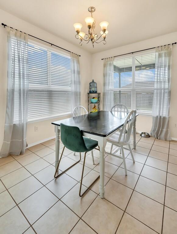 tiled dining room with a wealth of natural light and an inviting chandelier