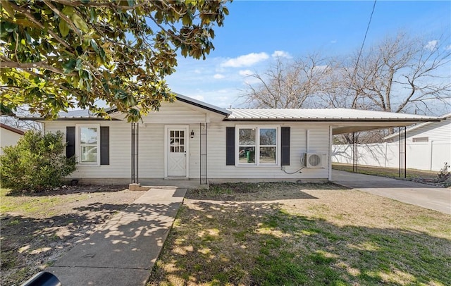 view of front facade with ac unit, concrete driveway, metal roof, fence, and a front lawn