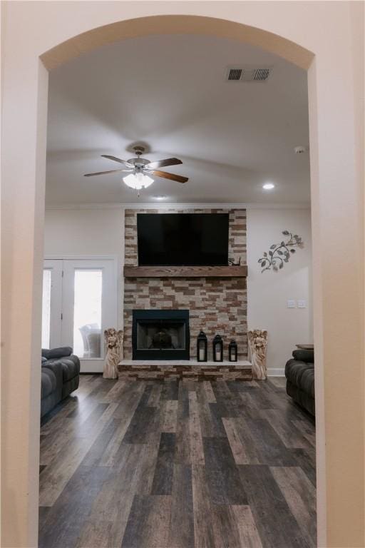 living room with dark hardwood / wood-style floors, ceiling fan, ornamental molding, and a fireplace