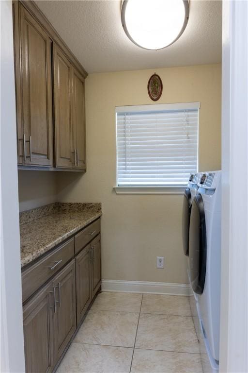 laundry area with cabinets, light tile patterned floors, washer and dryer, and a textured ceiling