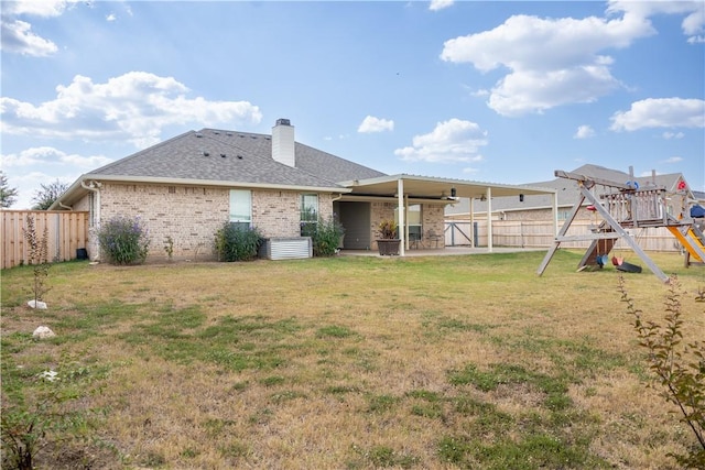 rear view of house featuring a playground, a yard, and a patio