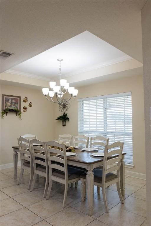 tiled dining area with a tray ceiling, ornamental molding, and a notable chandelier