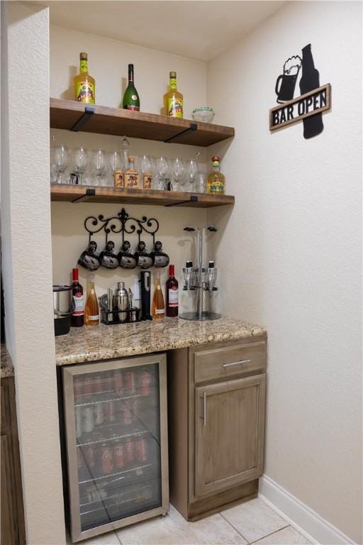 bar featuring light stone counters, light tile patterned flooring, and beverage cooler