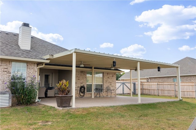 back of property featuring ceiling fan, a yard, and a patio