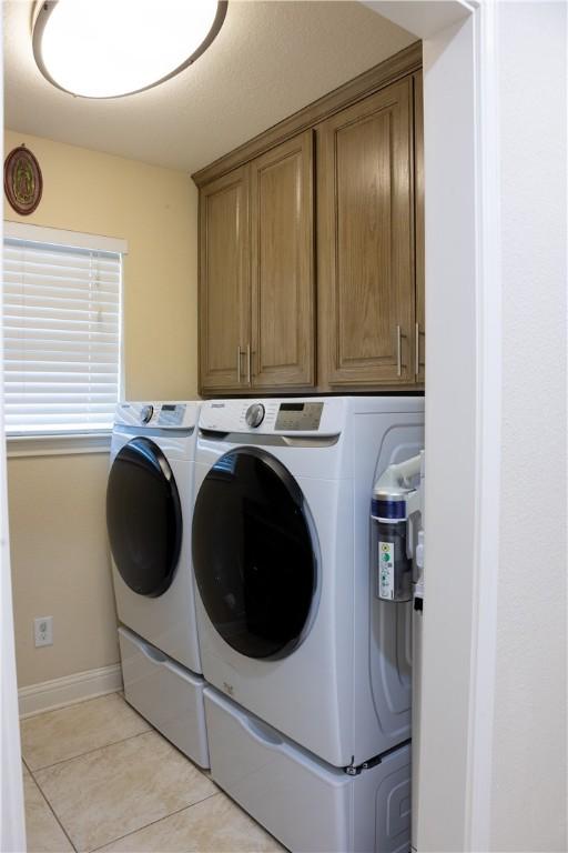 laundry area with cabinets, washer and clothes dryer, and light tile patterned flooring